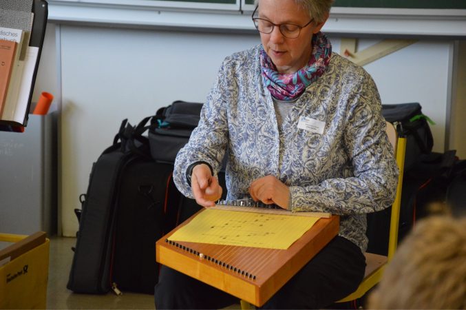 Anke Spindler sitzt vor einer Zauberharfe und einem gelben Notenblatt