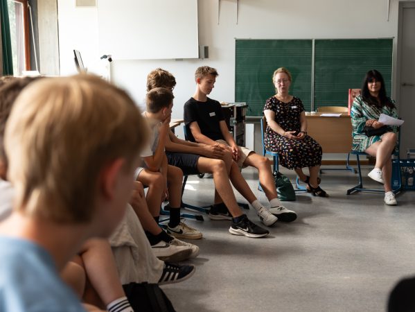 Schülerinnen und Schüler sitzen für den Workshop im Kreis zusammen