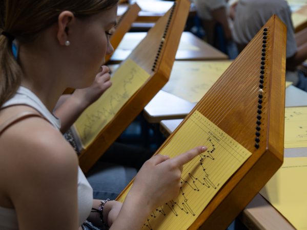 Schülerin zeigt auf die Notenschrift eines Notenblatts auf ihrer Zauberharfe