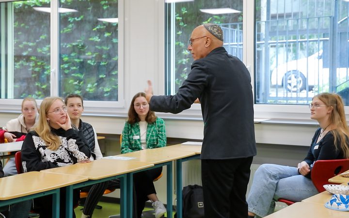 Terry Swartzsberg steht vor den aufmerksam zuhörenden Schüler*innen und erklärt etwas